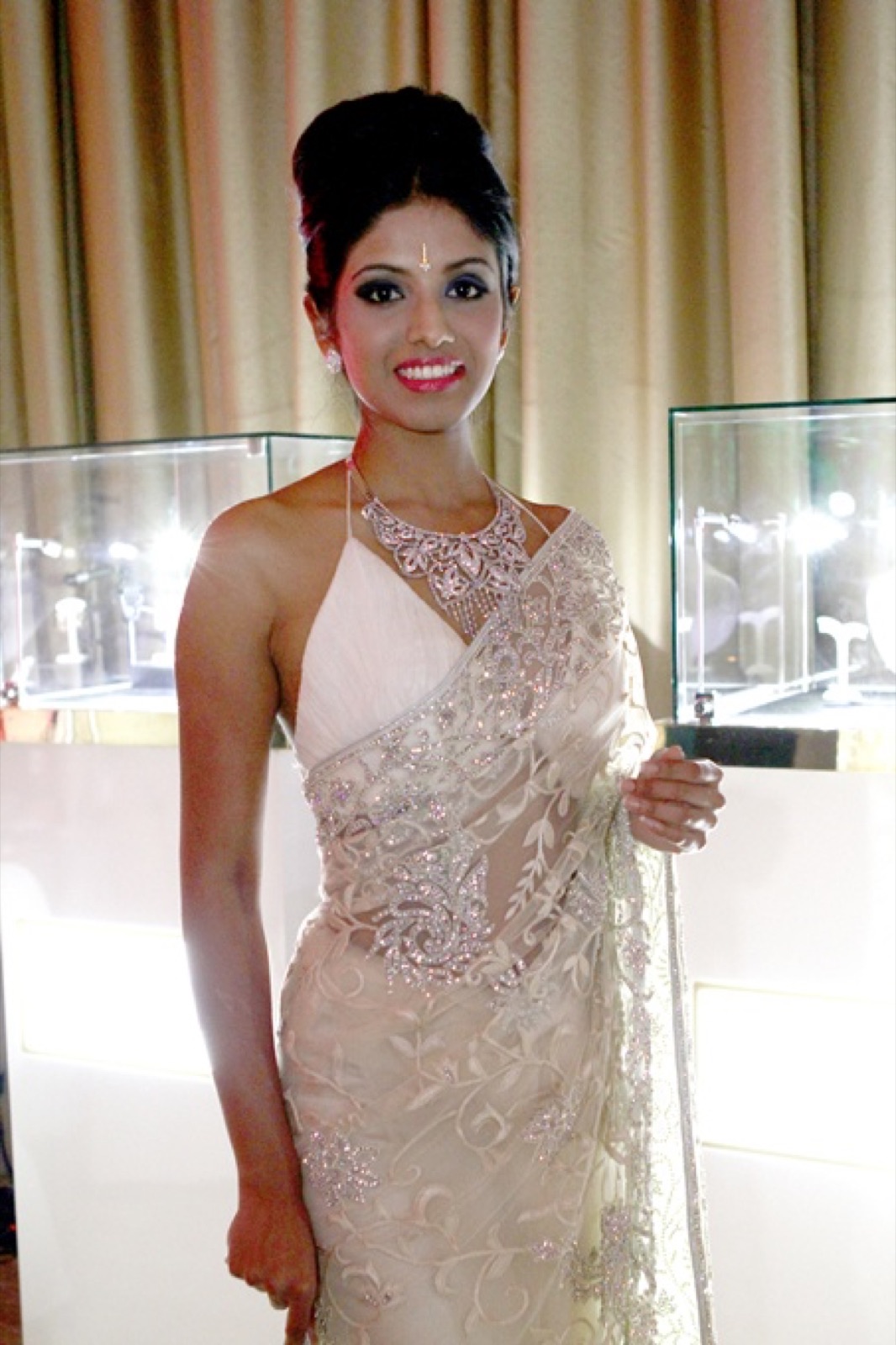 A model wearing a diamond necklace beside the vitrines