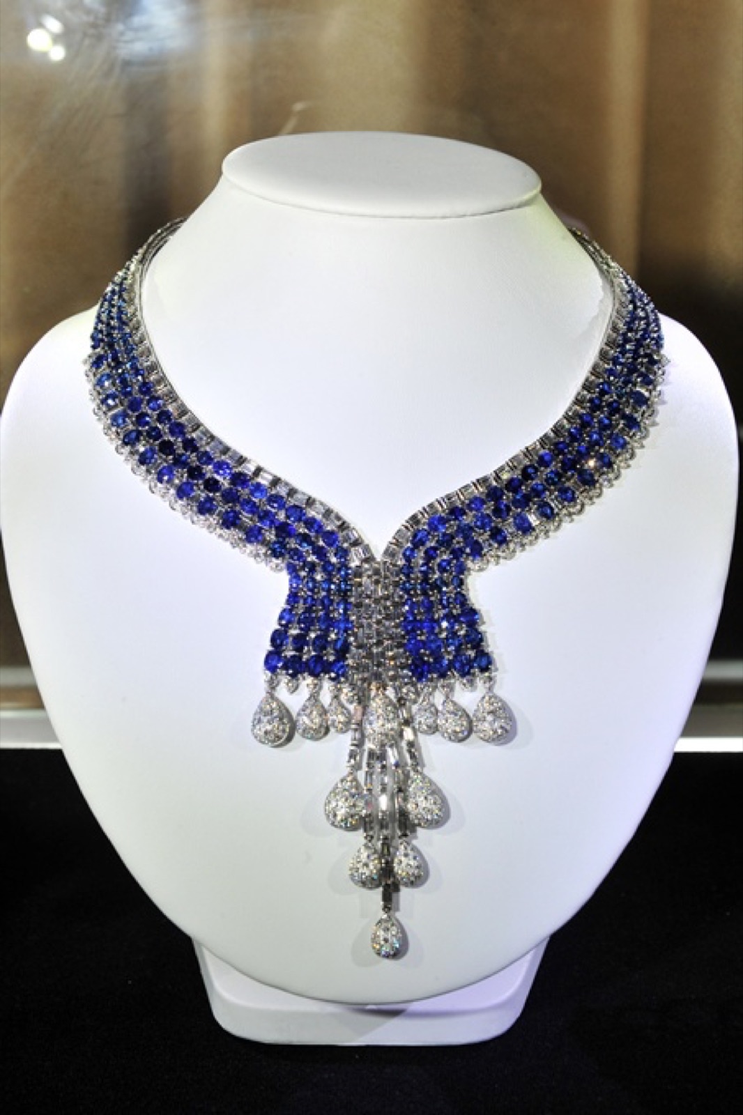 A sapphire and diamond necklace on a display bust, photographed at the couture evening