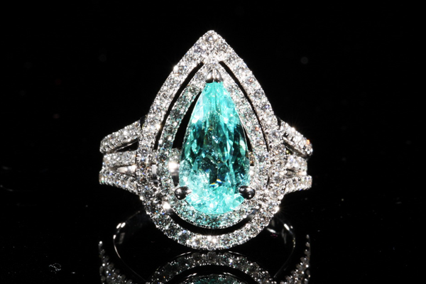A pear cut gem of luminous lagoon blue within a double halo of brilliant cut diamonds.