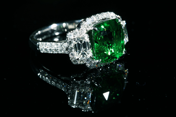 An emerald green cabochon embraced by a halo of brilliant cut diamonds.