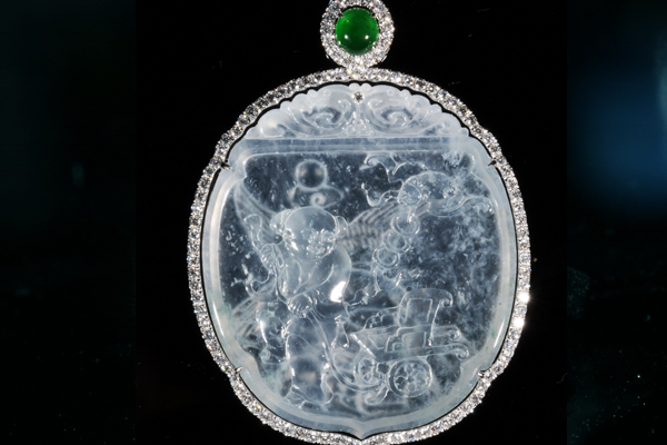 A carved icy jadeite plaque crowned by a vivid green cabochon and traced in diamonds.