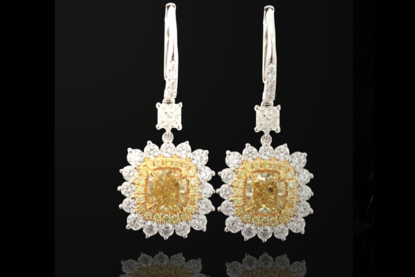 Cushion cut stones of golden yellow within twin surrounds of pale and white brilliants.